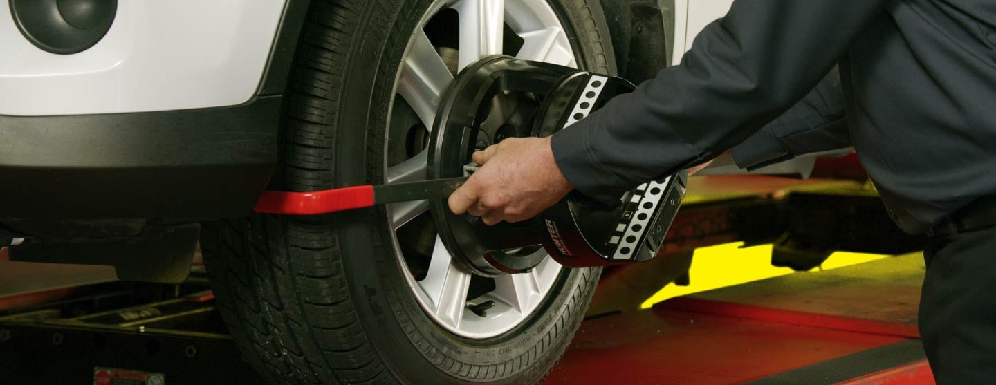 Person holding tire to show what can happen if you ignore wheel alignment